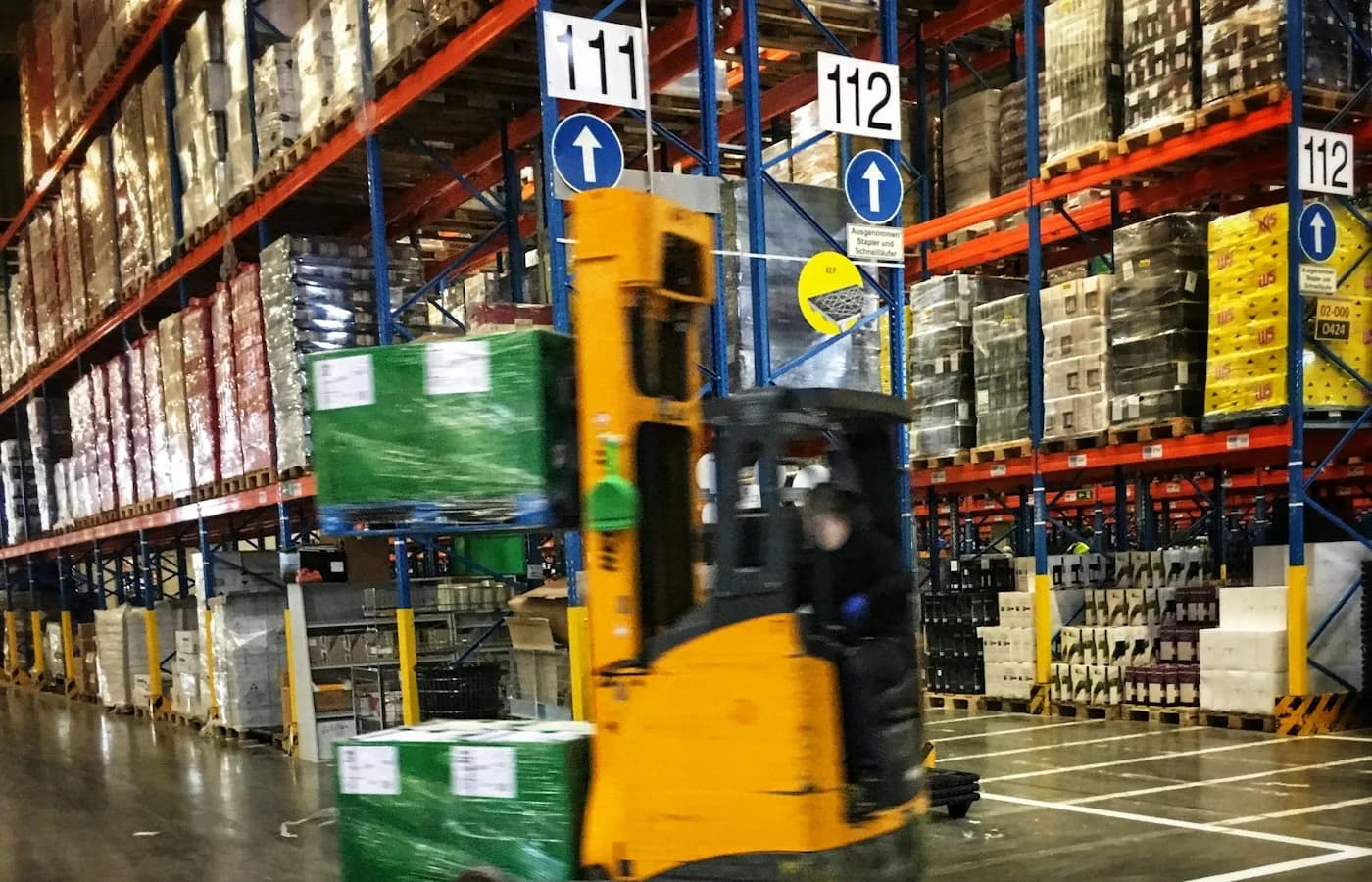 Chariot élévateur en manoeuvre dans un entrepôt entre des racks de palettes